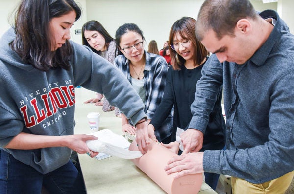 A group of students work on a simulated training with a manikin leg