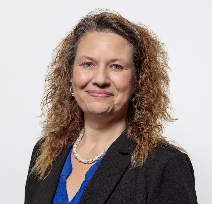 Woman in suit jacket and blue shirt smiles