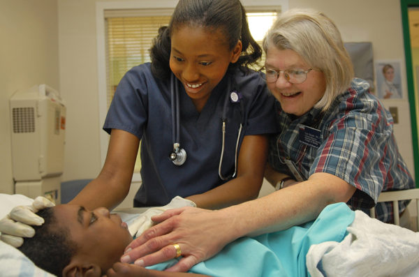 student and faculty examine child patient