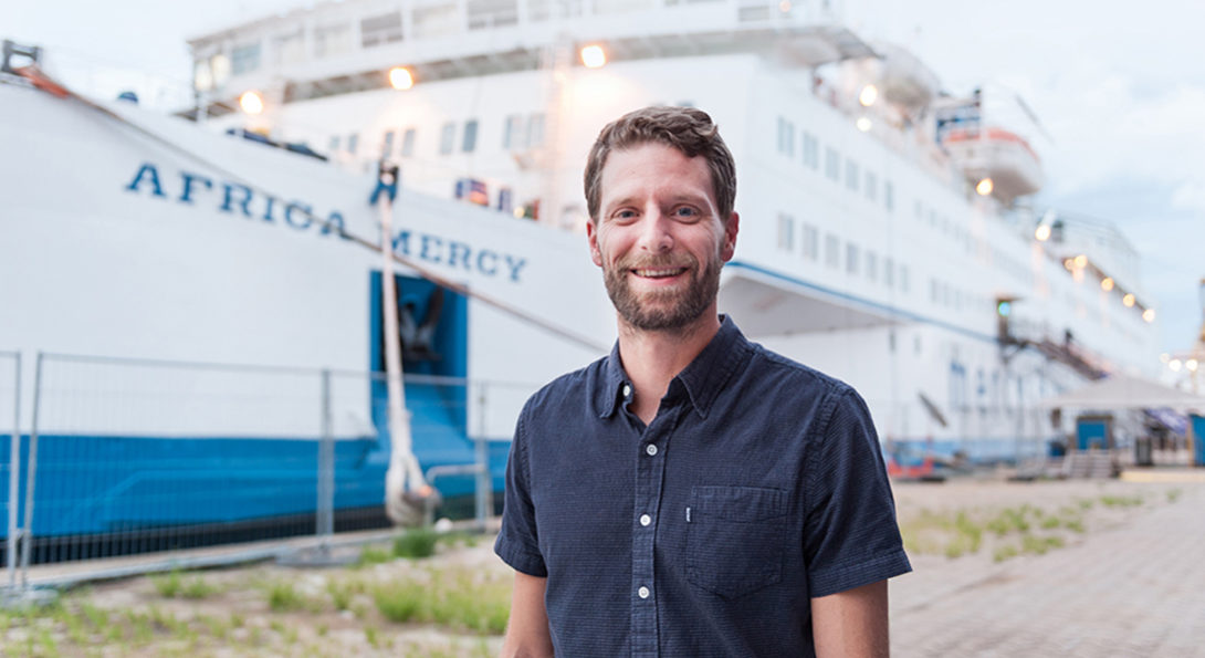 Alumnus Nate Claus standing in front of Africa Mercy ship