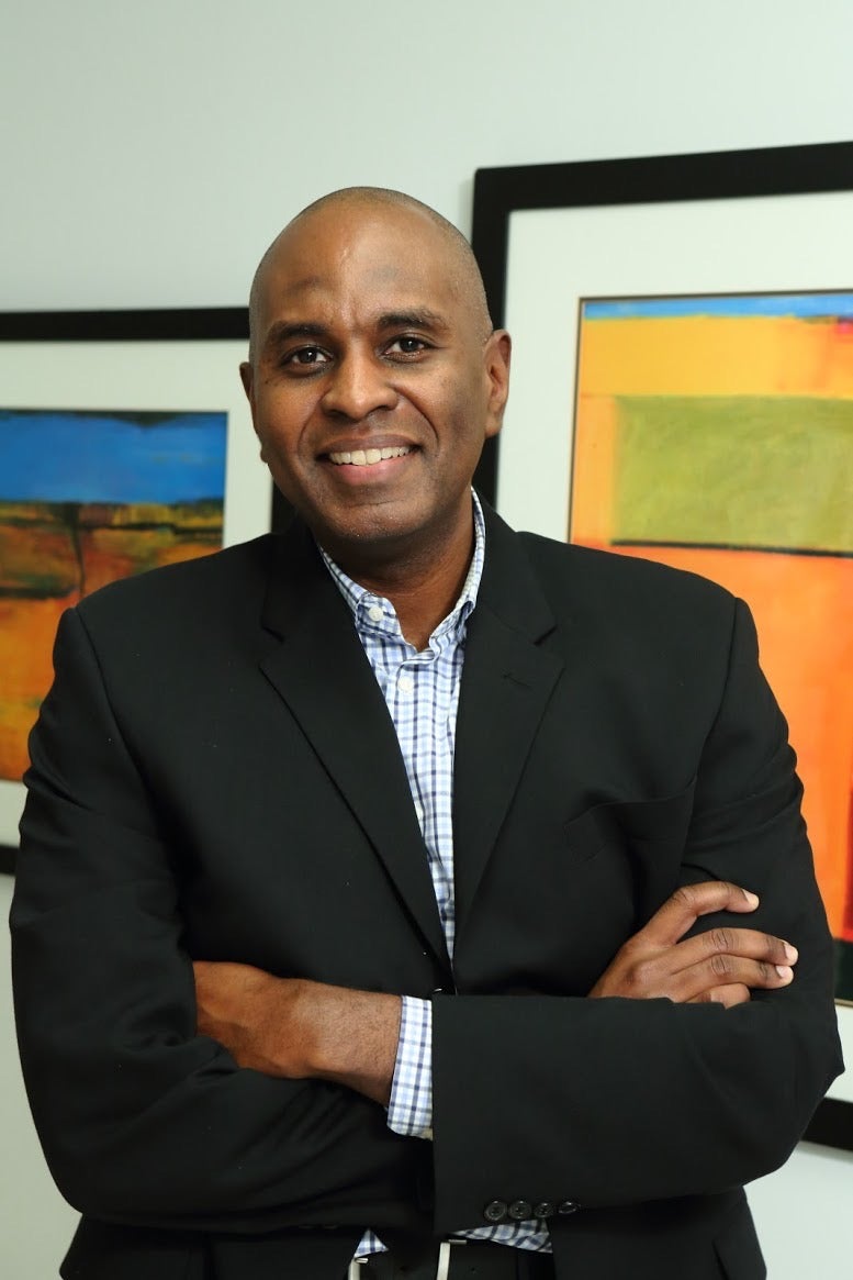 man smiling in front of framed pictures