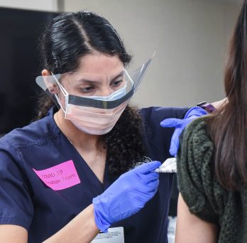 Student administers COVID-19 vaccine to patient who arm is only visible 