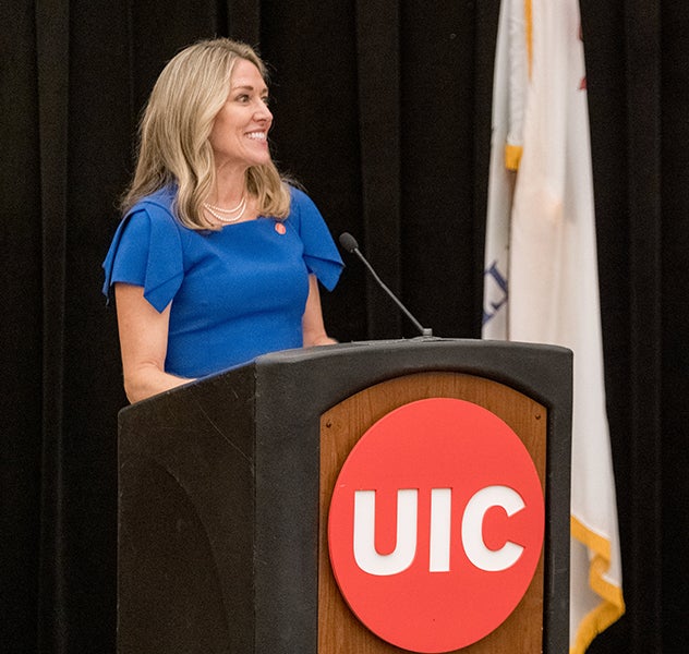 Susan Corbridge standing at podium with UIC sign on it