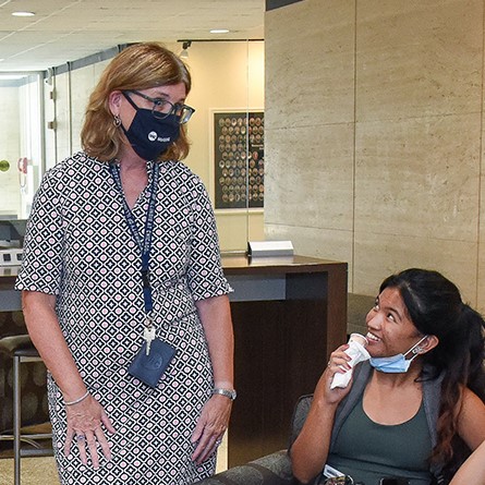 Dean Eileen Collins, wearing a mask, visits with a student in the lobby of the College of Nursing building in Chicago