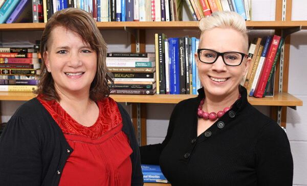 Paige Ricca and Wendy Bostwik standing in front of a book shelf