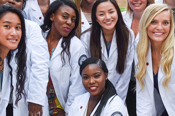 A group of happy students crowd together to smile at camera