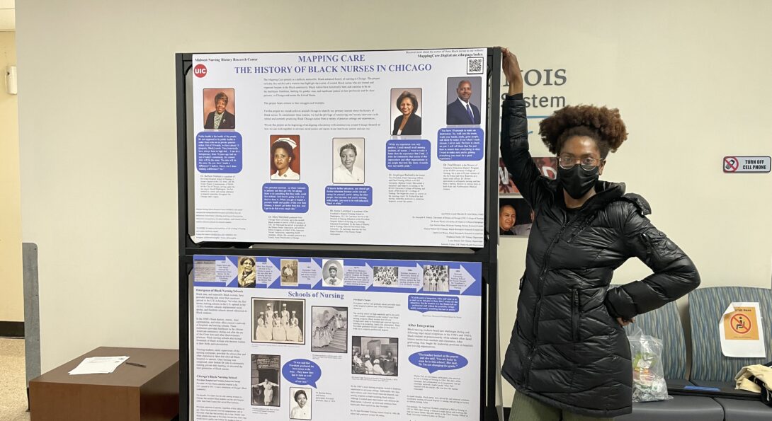 Kennedy Forbes, a UIC undergraduate and intern on the project, poses with the Mapping Care: Black Nurses in Chicago traveling exhibit.
