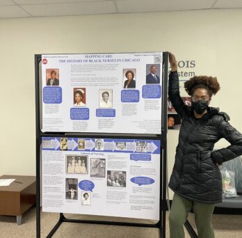 Kennedy Forbes, a UIC undergraduate and intern on the project, poses with the Mapping Care: Black Nurses in Chicago traveling exhibit.
                  
