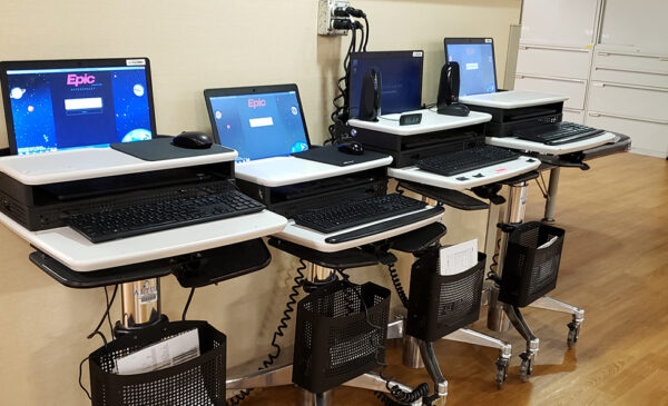 Row of laptops on rolling carts with screen showing Epic software logo