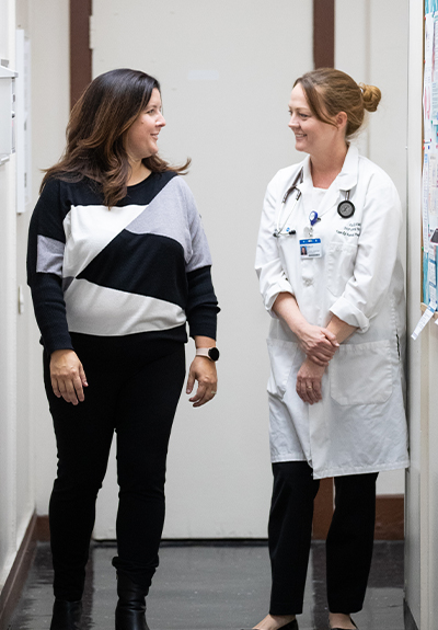 two women talk in the hallway in a clinical setting