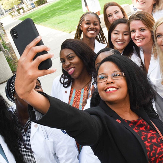 woman takes selfie of herself and a diverse group of nursing students