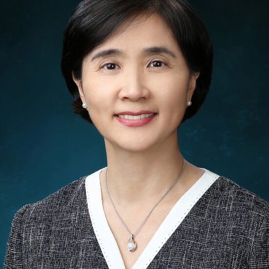 Portrait of an Asian woman with short, dark hair wearing gray-and-white suit jacket