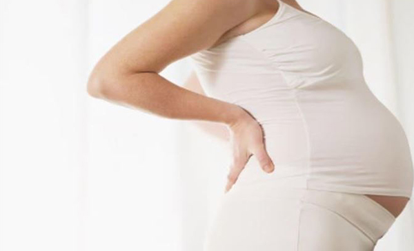 A pregnant woman holds her back