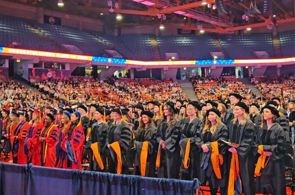 Group of graduates standing in a large auditorium
