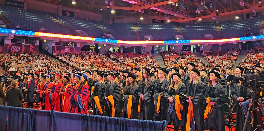 Large group of graduating students stand and applaud