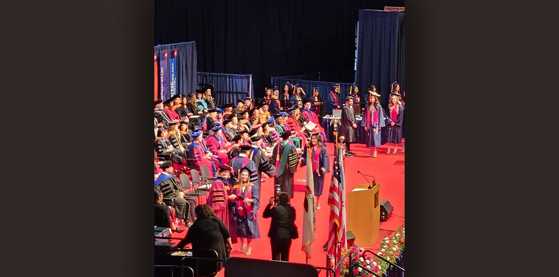 Graduates walk across stage to accept degree