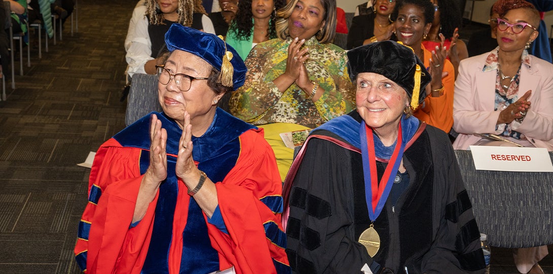 Two women sit and applaud