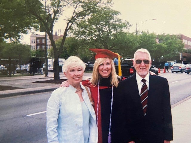 Katie Moriarty wears graduation cap and gown while flanked by her parents