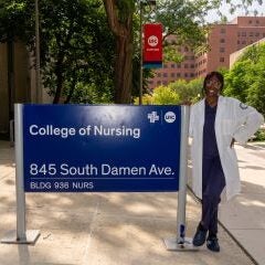 Female student next to College of Nursing sign