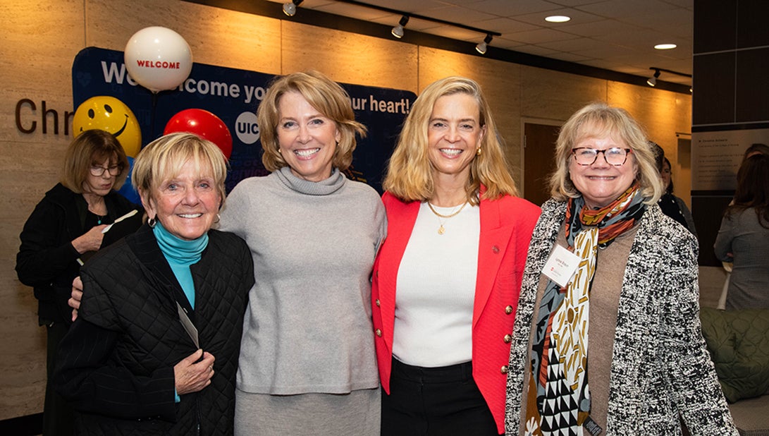 Four women pose and smile for camera