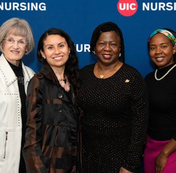 Four women stand side by side to pose for an photo in front of the College of Nursing backdrop
                  