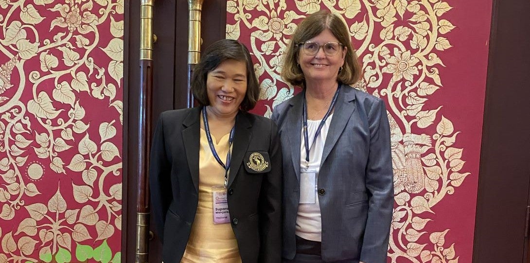 Two women stand in front of ornately decorated doors