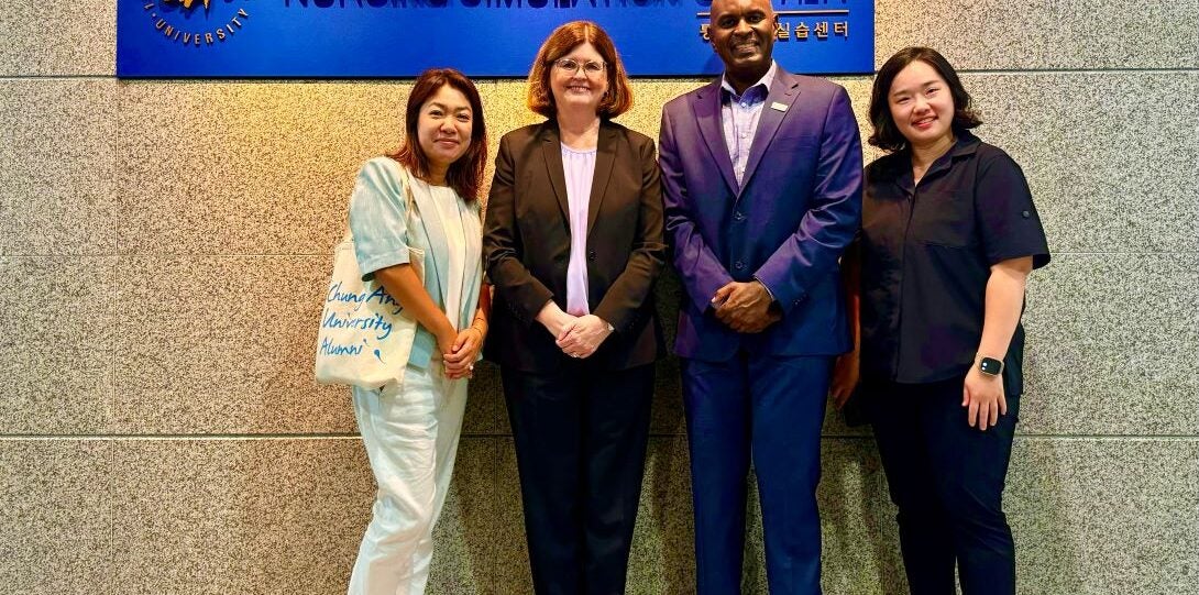 A group of four stands in front of a nursing simulation center