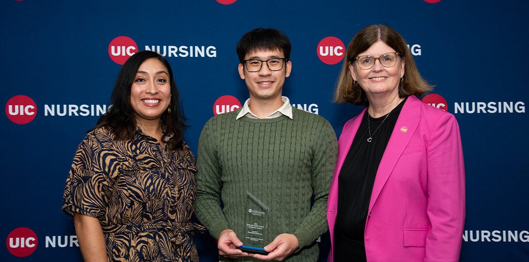 Three pose for picture with award