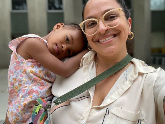 A woman wearing glasses holds a young child.