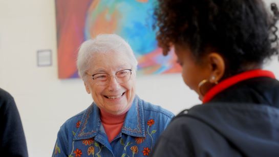 Woman with short white hair smiles while talking