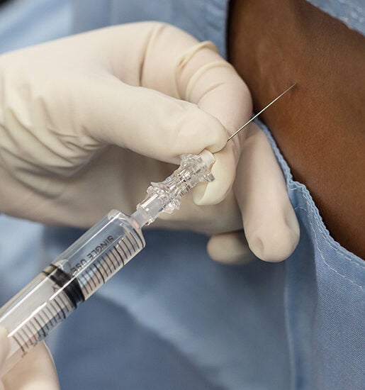 Close up image of an anesthesia professional inserting a needle into a patch of skin