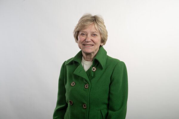 Woman in green coat smiles for photograph
