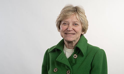 Short-haired woman in green jacket smiles at camera