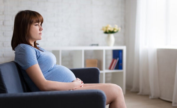 pregnant woman sits on couch